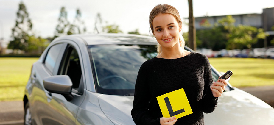 learner driver girl holding up L plate and keys