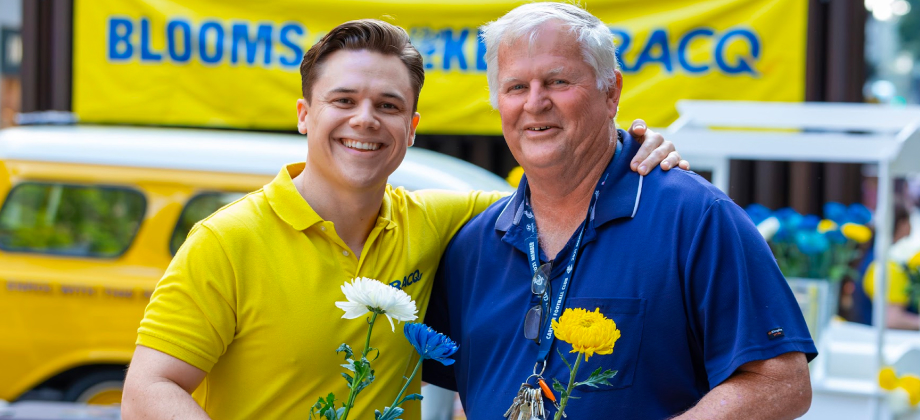 Two men standing together holding bouquet of flowers for "blooms for blokes" initiative