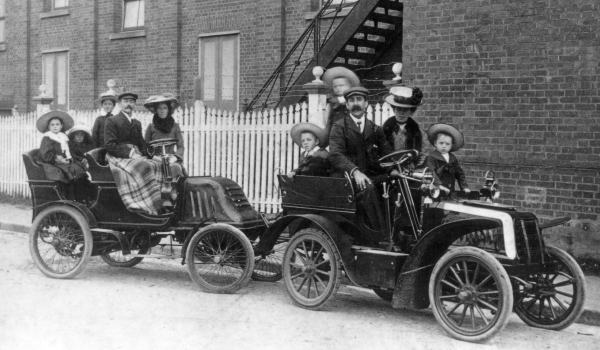 Black and white negative of people posing inside 2 vintage vehicles