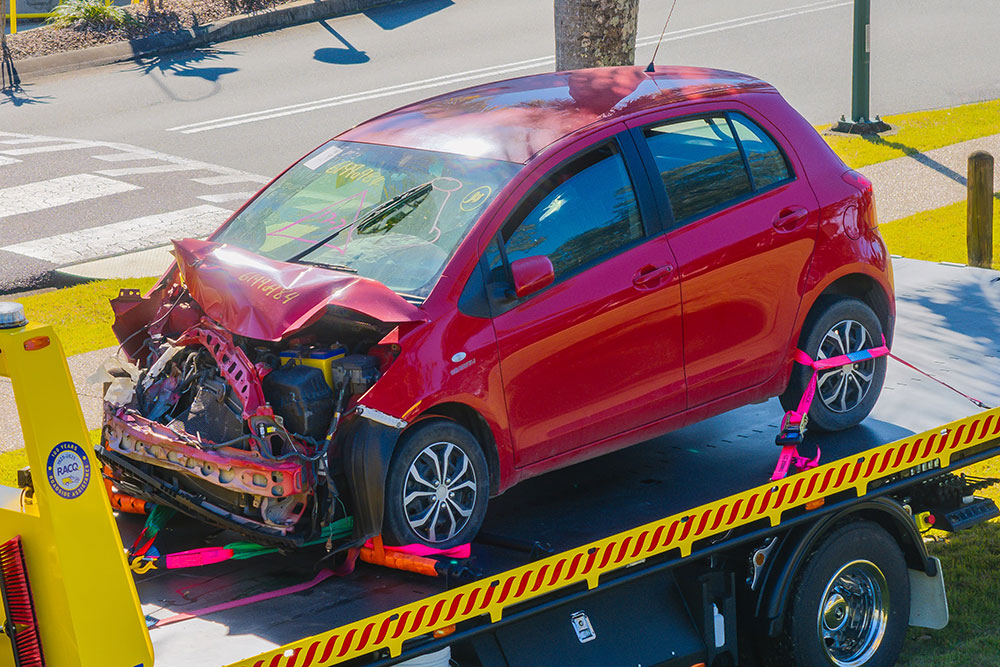 A badly damaged vehicle on the back of an RACQ truck.