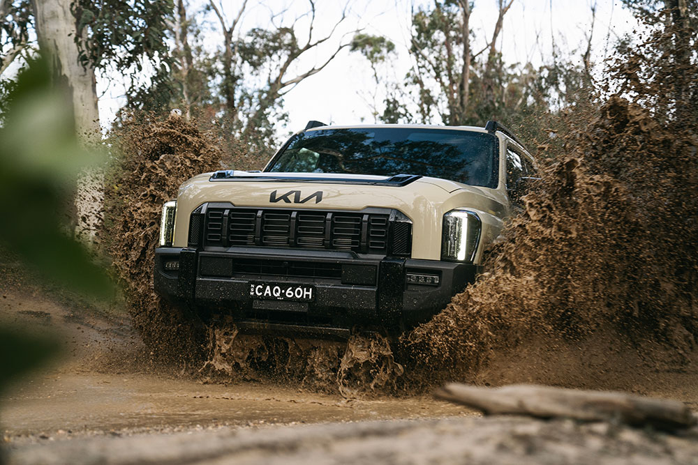 Kia Tasman being driven through muddy water.
