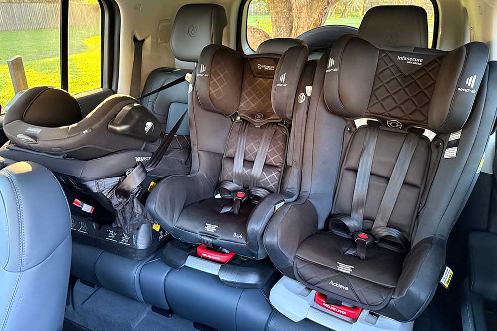 Back seat of a Denza B5 with three baby seats attached.