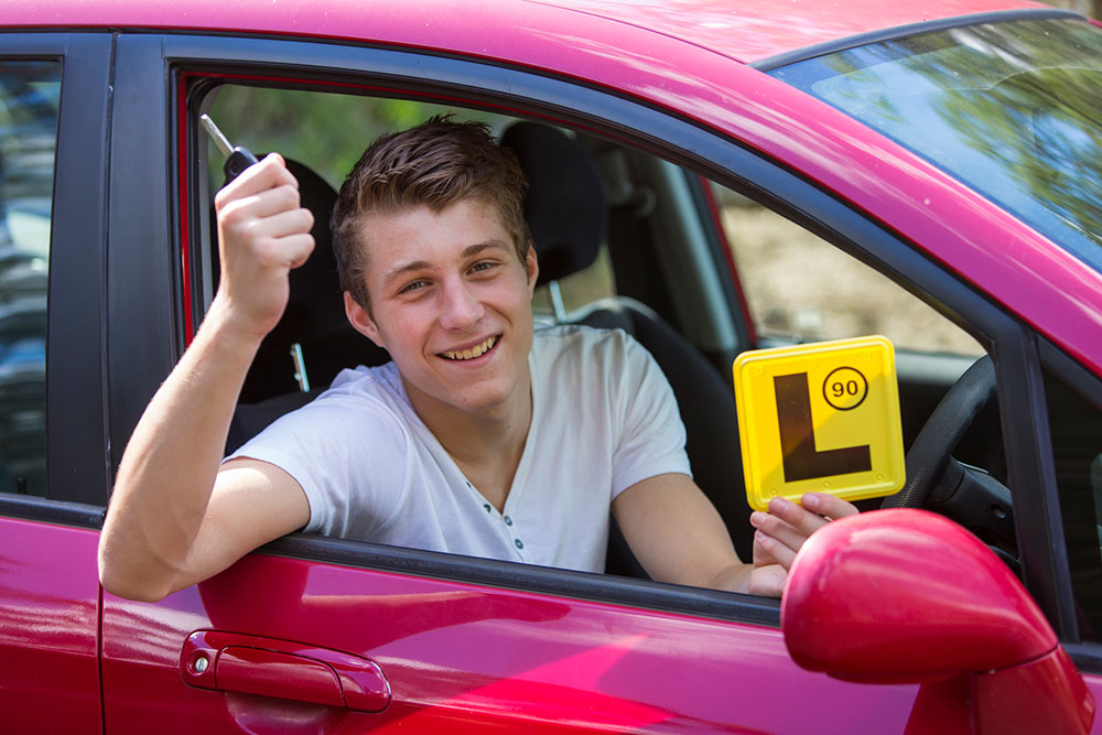 Learner driver holds up car keys while behind the wheel.