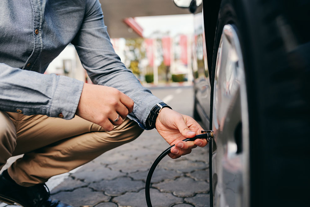 Man putting air into his car tyres.