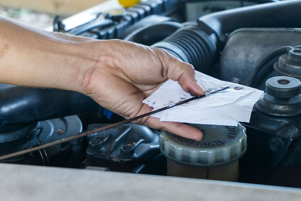 Man checks engine oil level in his car.