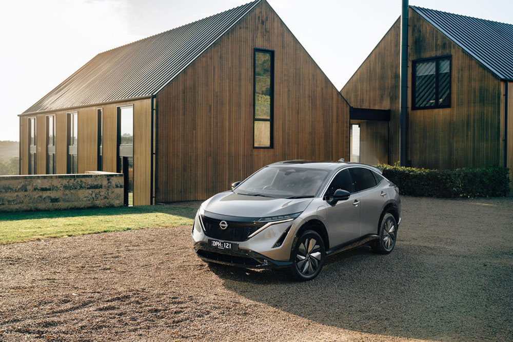 Nissan Ariya in front of rural buildings.
