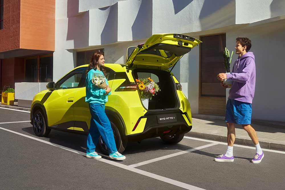Couple standing at the back of BYD Atto 1 with its boot open