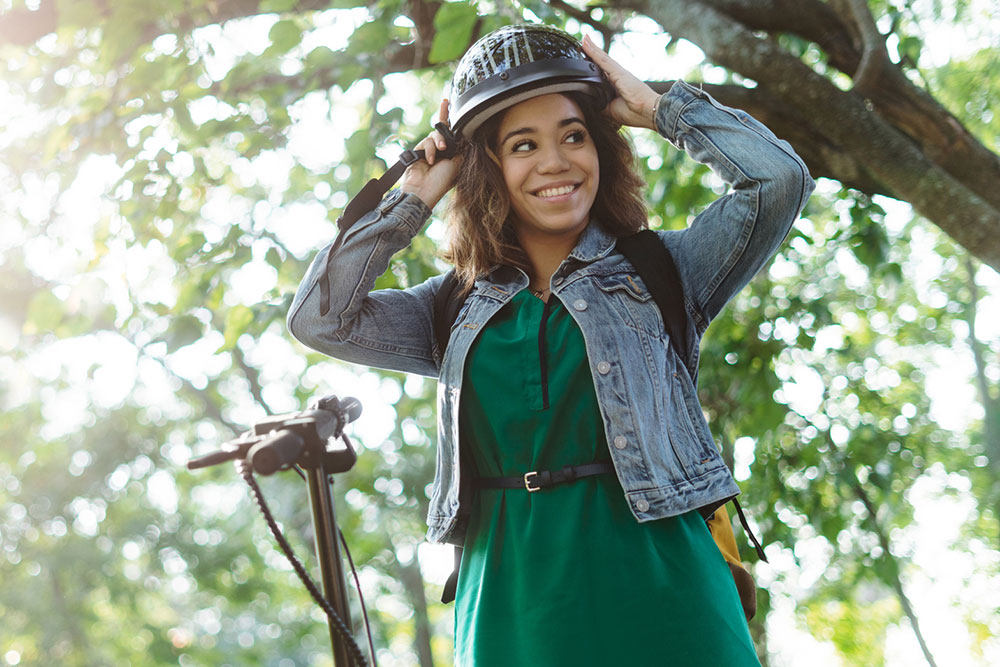 Young woman fitting helmet before riding e-scooter.