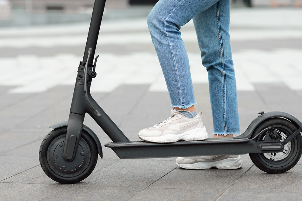 Woman stepping on to e-scooter.