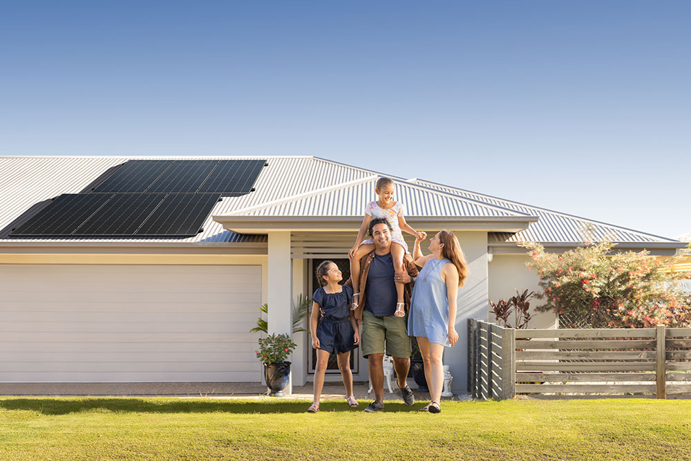 Family in front of house with solar panels on the roof.