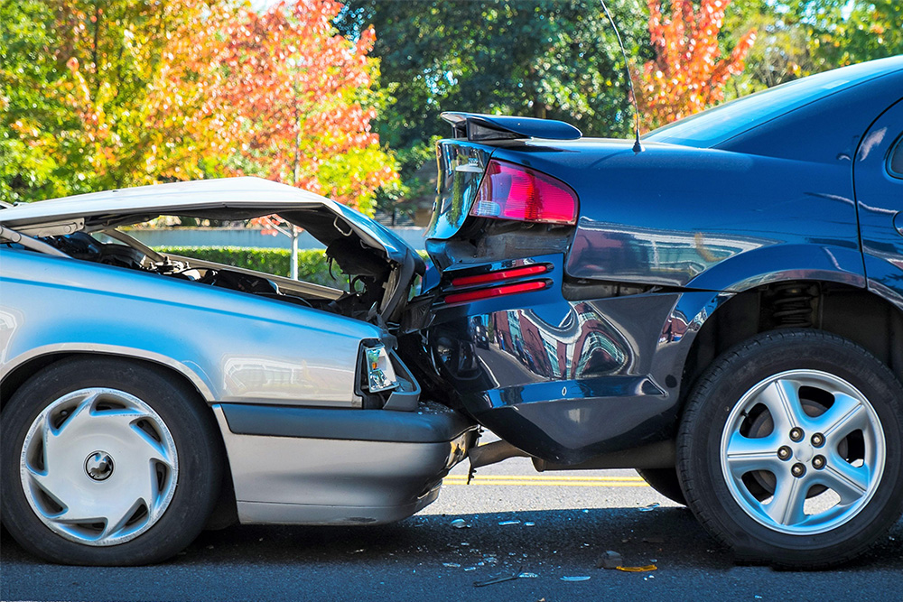 two cars with damaged bumpers and hood on the road