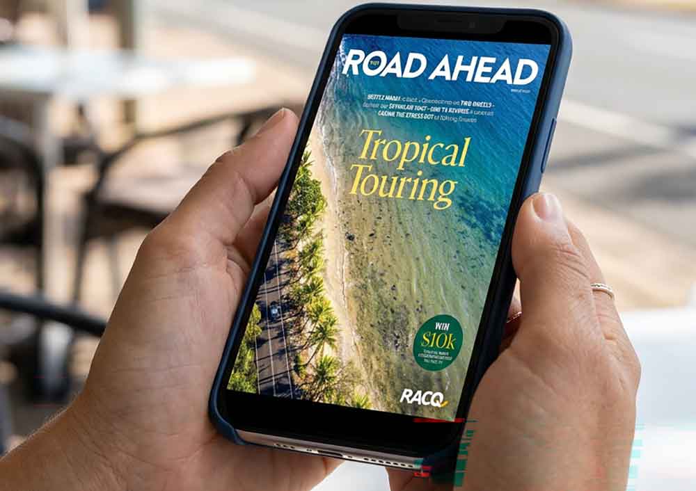 Someone holding mobile phone with cover of The Road Ahead magazine on it.