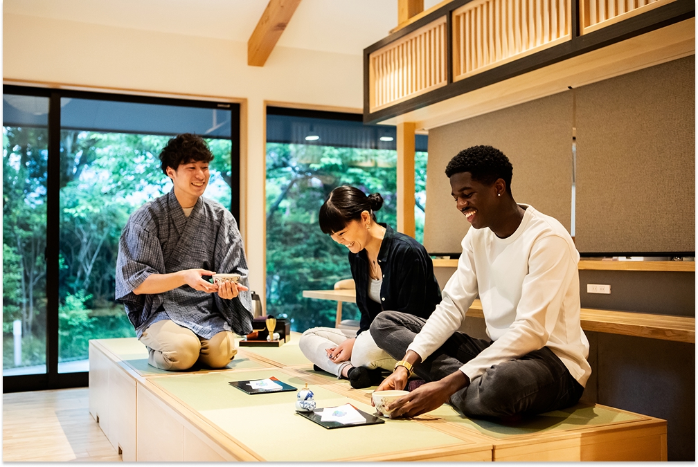 man teaching two guests how to make matcha tea ceremony at a Japanese guesthouse