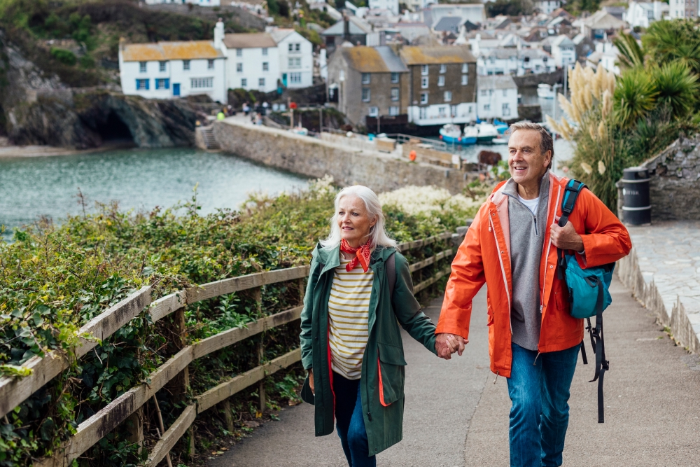 older couple walking outside holding hands in a European costal landscape