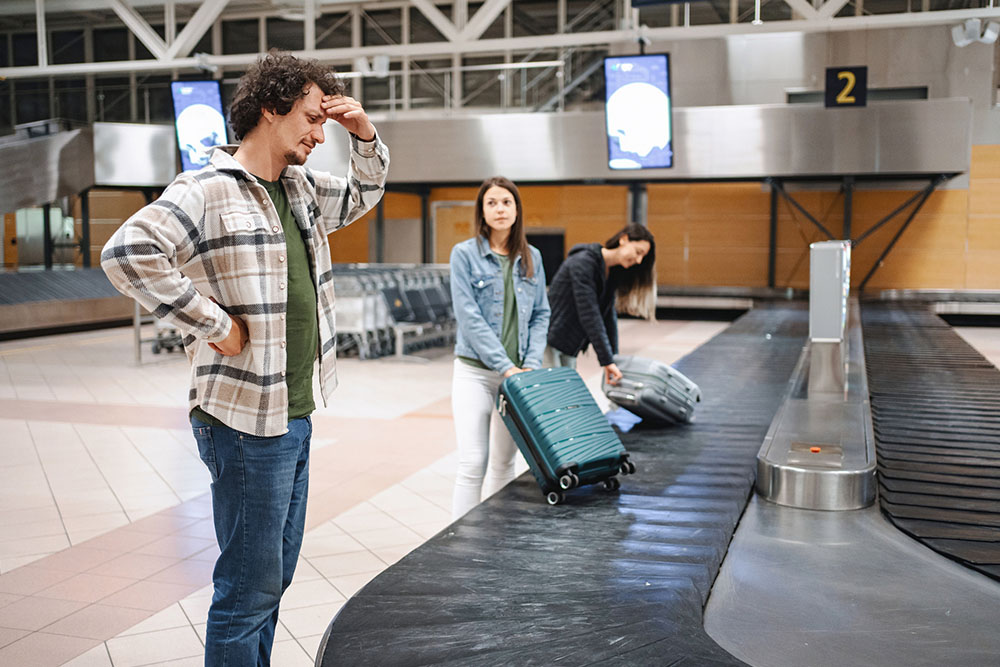 Man looking stressed standing next to the baggage carousel