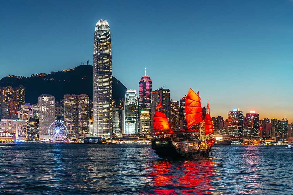 A traditional Chinese junk sails on Victoria Harbour at dusk