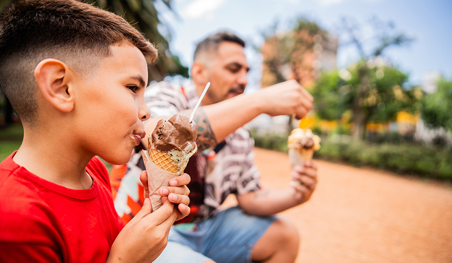 Father and son eating ice-cream together in an outdoors setting