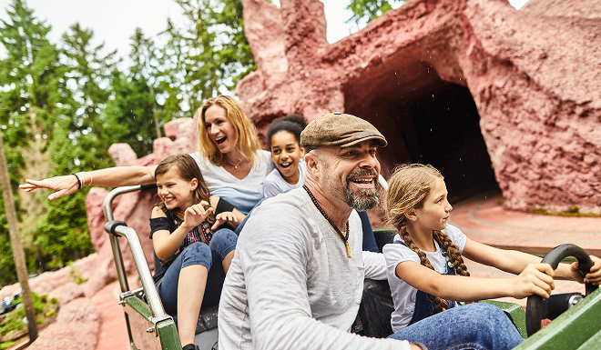 Happy family sitting in a passenger cart on an amusement park ride