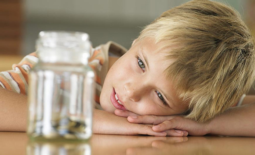 Young-boy-looking-at-money-jar