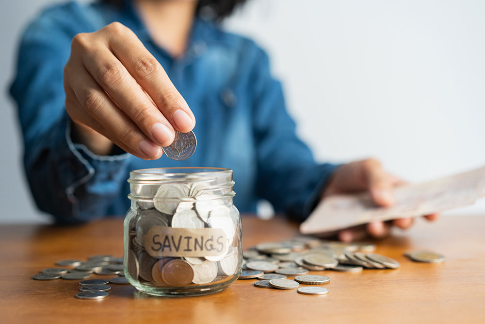 Woman putting coins in a jar marked savings