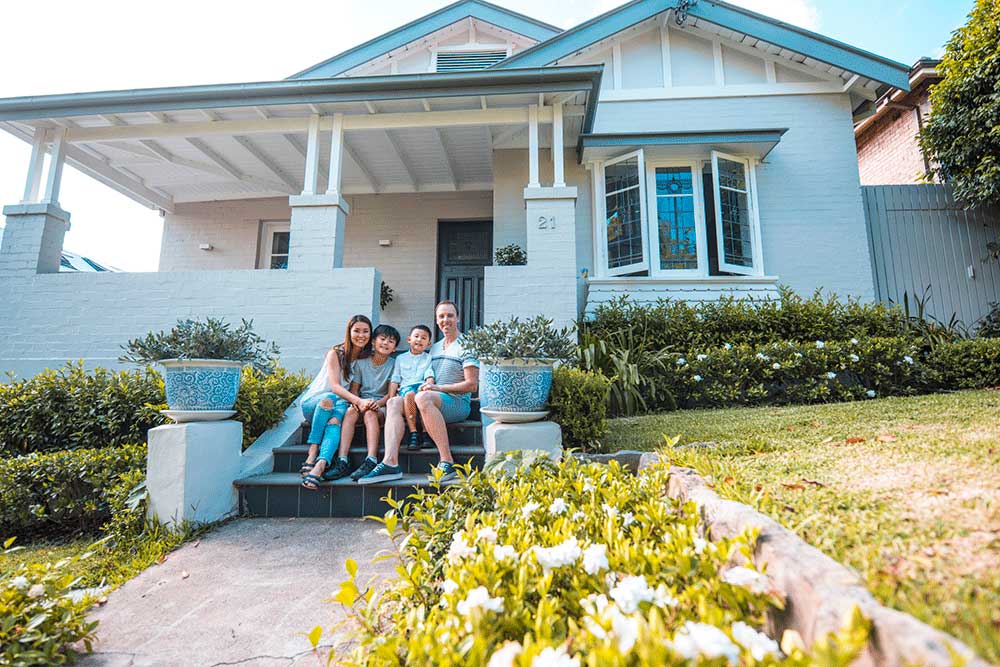 Young family sitting on the front steps of their home.