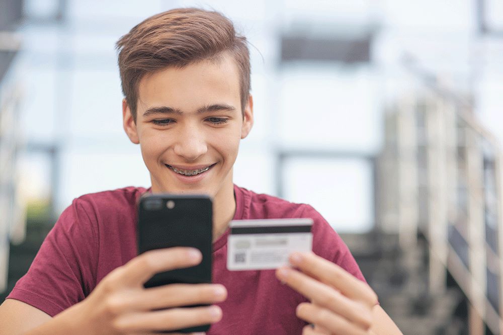Teenager looking at credit card and phone