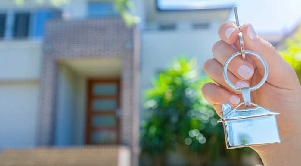 Person holding keys outside the front of a house