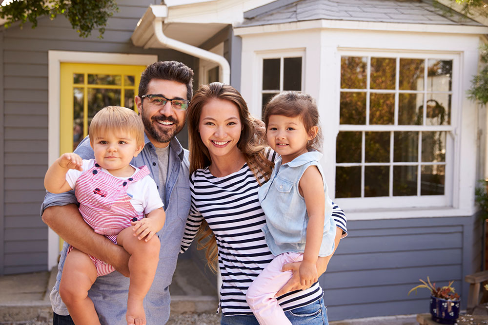 Dad mum and 2 kids standing outside a house