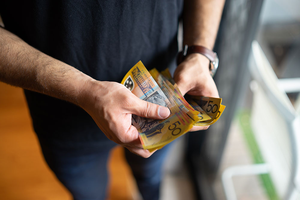 Man counting a stack of $50 notes