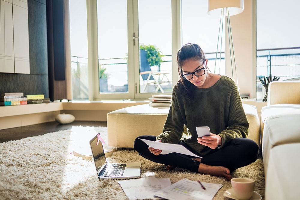Young woman on phone while checking financces.