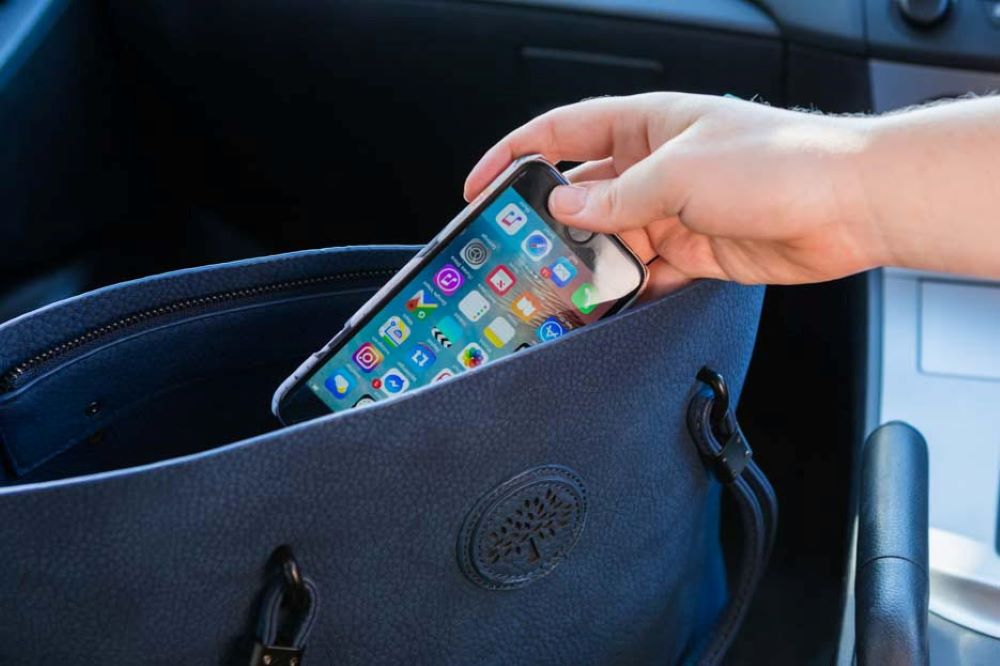 Person slipping mobile phone into bag pocket