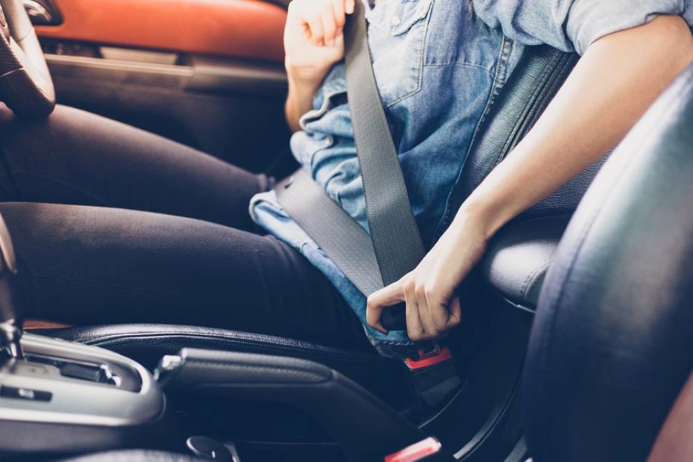 Driver buckling up seat belt in car