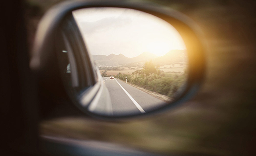 Car side mirror showing road behind