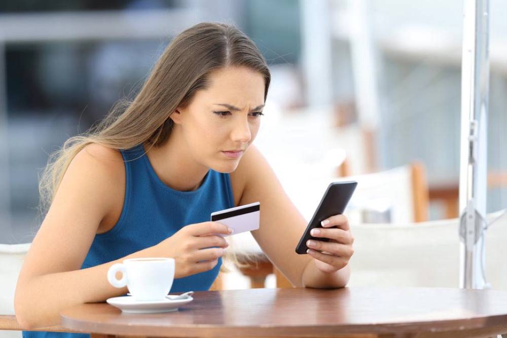 Woman staring at credit card and mobile phone