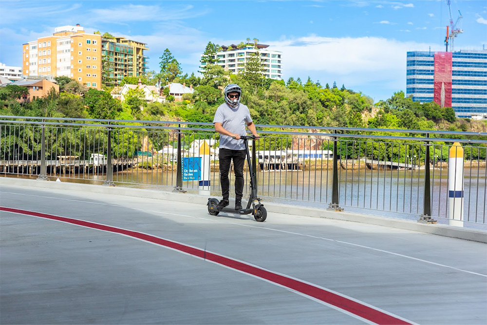 Man standing up riding e-scooter will full face helmet