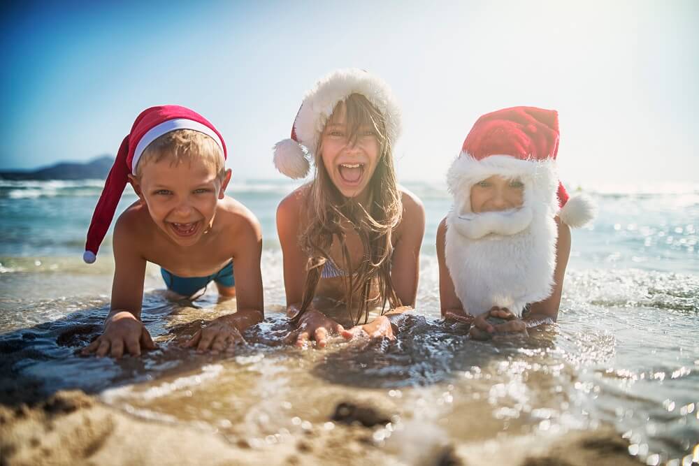 Kids playing in the surf with Christmas hats on.