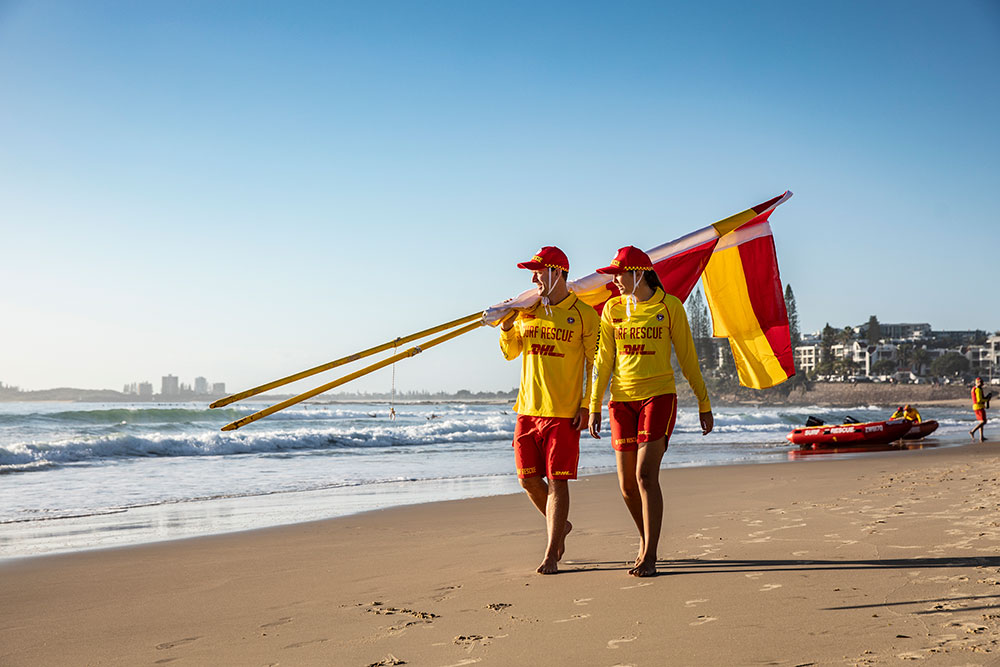 Two Queensland lifesavers walking along a beach.
