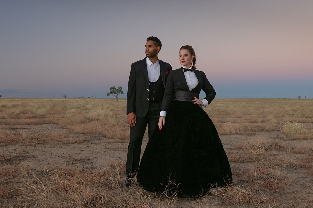 Two opera performers wearing formalwear in the outback