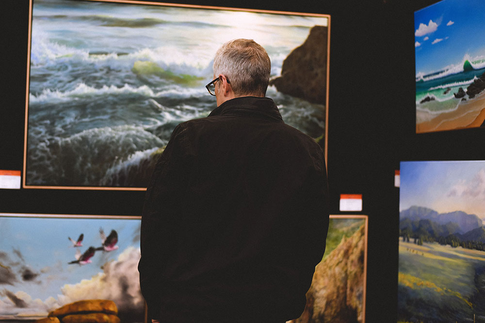 A man looks at painting displayed at The Doyles exhibition on the Gold Coast.