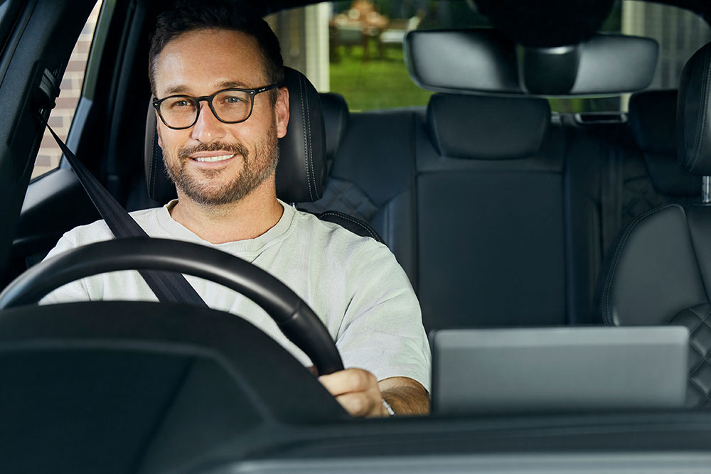 Man with glasses driving car.