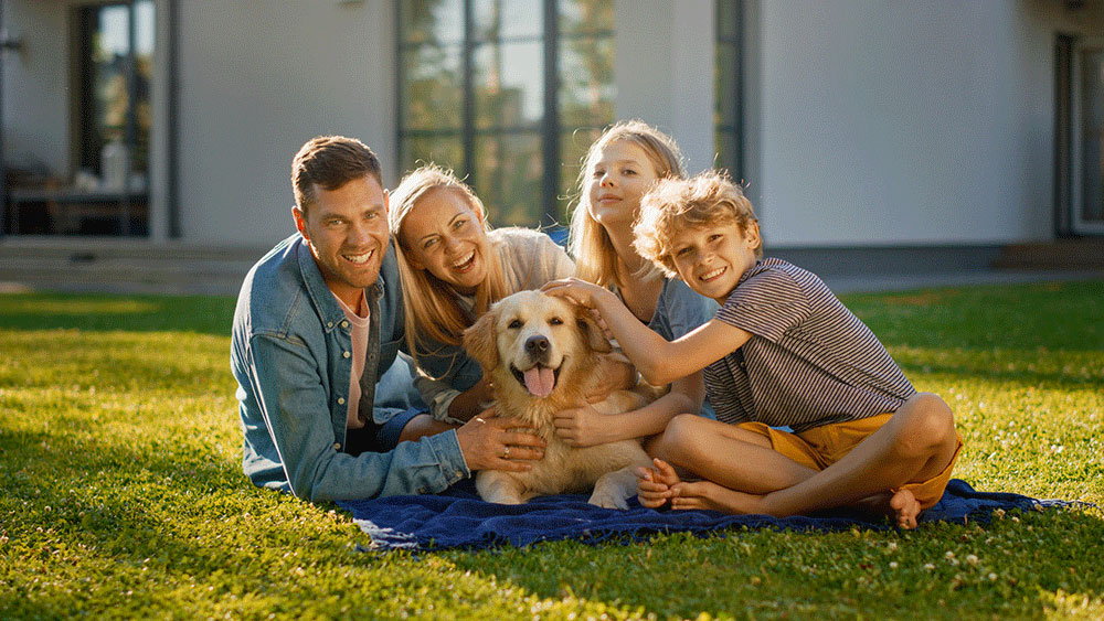 family of four sitting on the grass with a Labrador dog