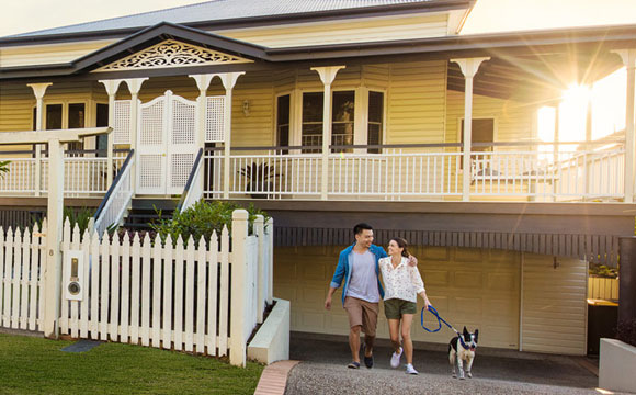 Man and woman standing outside of suburban home with pet dog