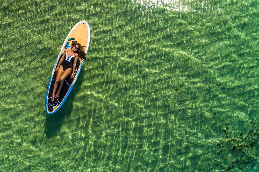 Woman laying on a stand up paddle board
