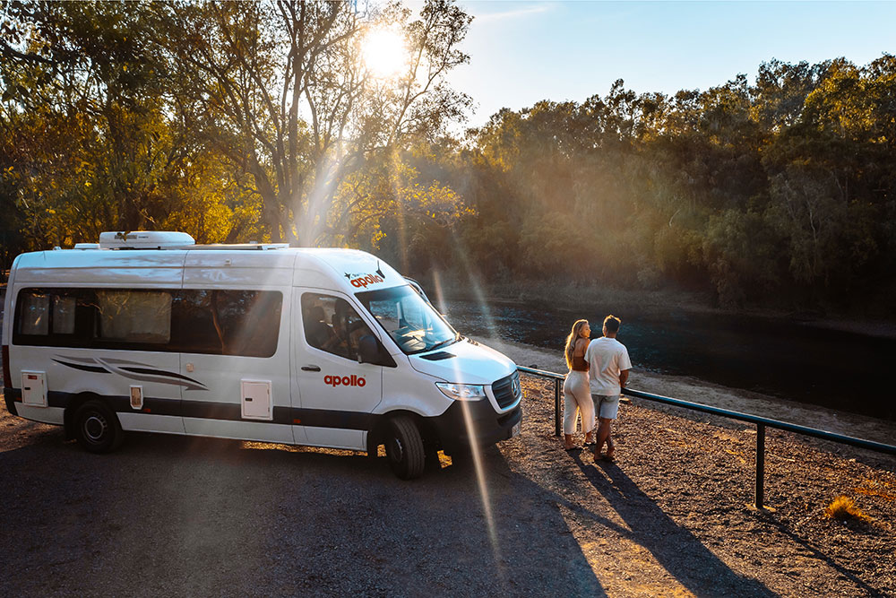 Couple standing beside Apollo camper van.
