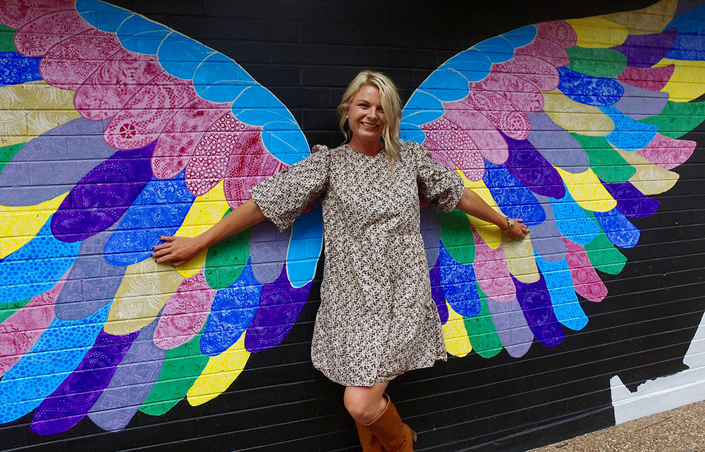 Woman standing in front of mural of wings