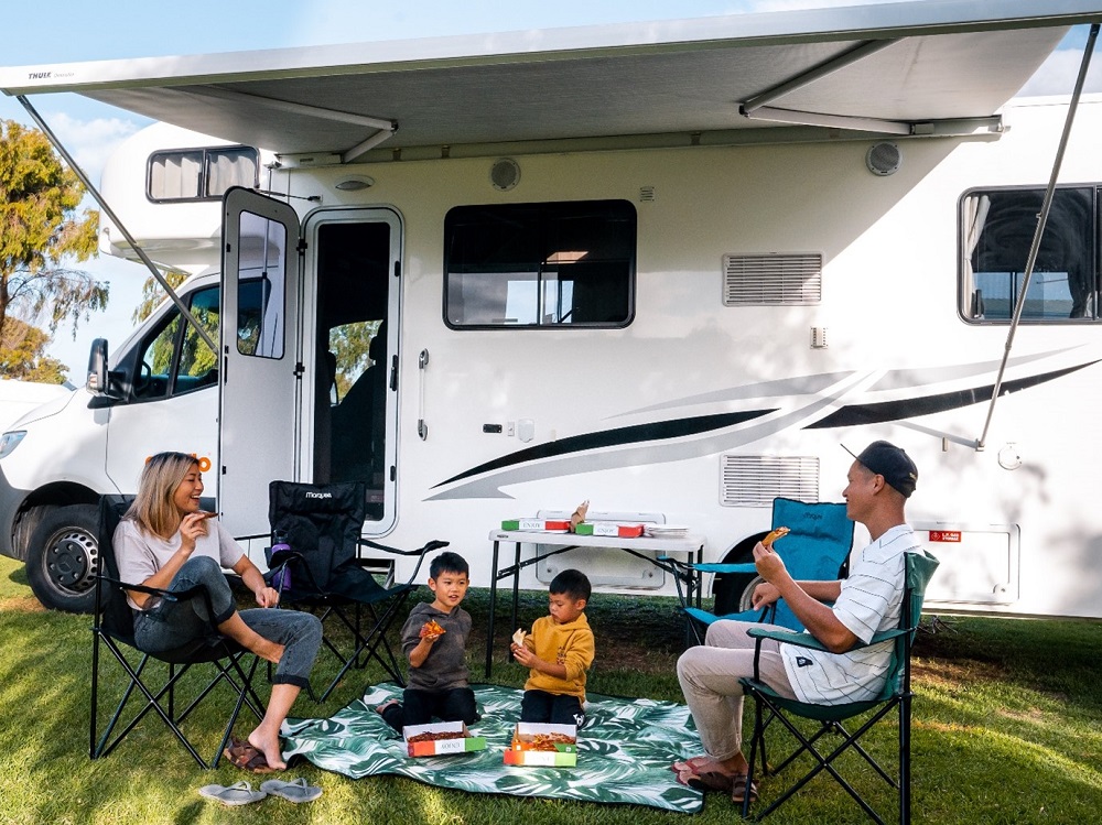 Family eating a picnic outside their Apollo campervan