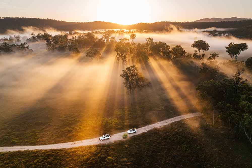 Two vehicle driving through the early morning light at Carnarvon National Park.
