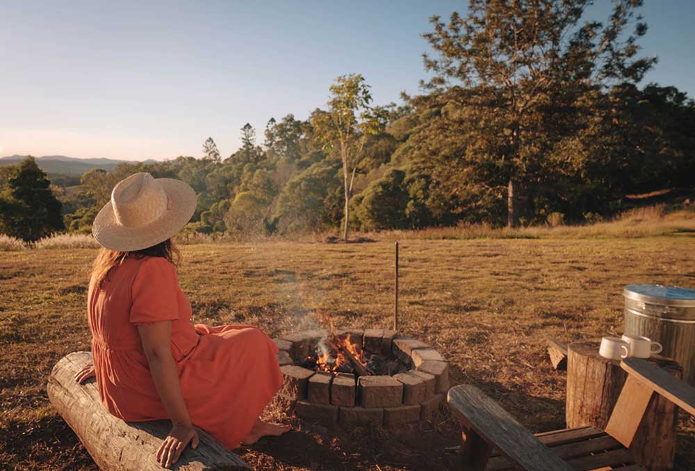 Woman sitting beside fire pit.