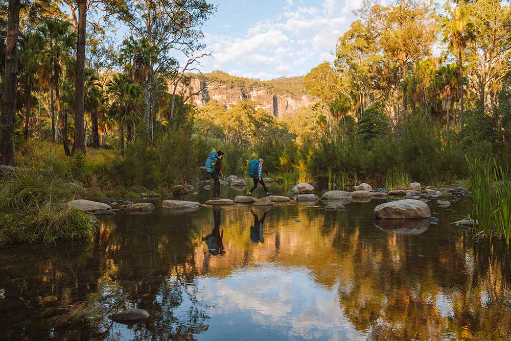 Hikers cross a creek in Carnarvon Gorge.