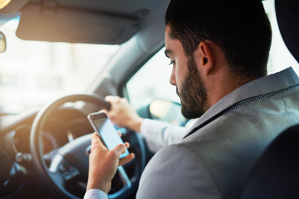 man looking at mobile phone while driving